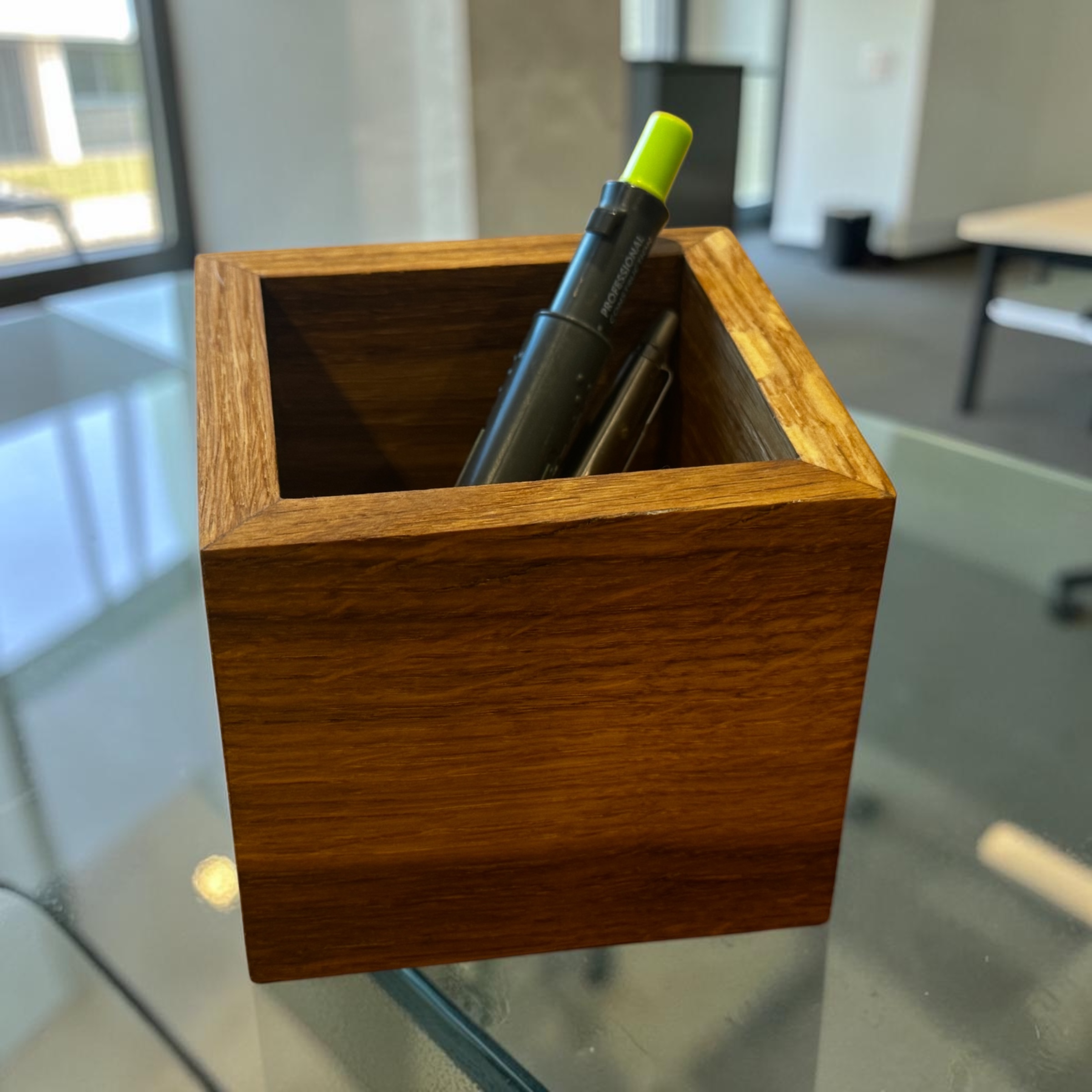 A square oak desk organiser on a glass desk.