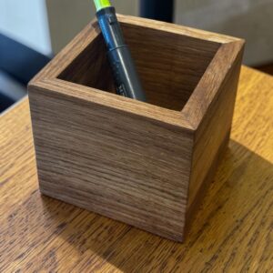 A square oak desk organiser on a wooden desk.