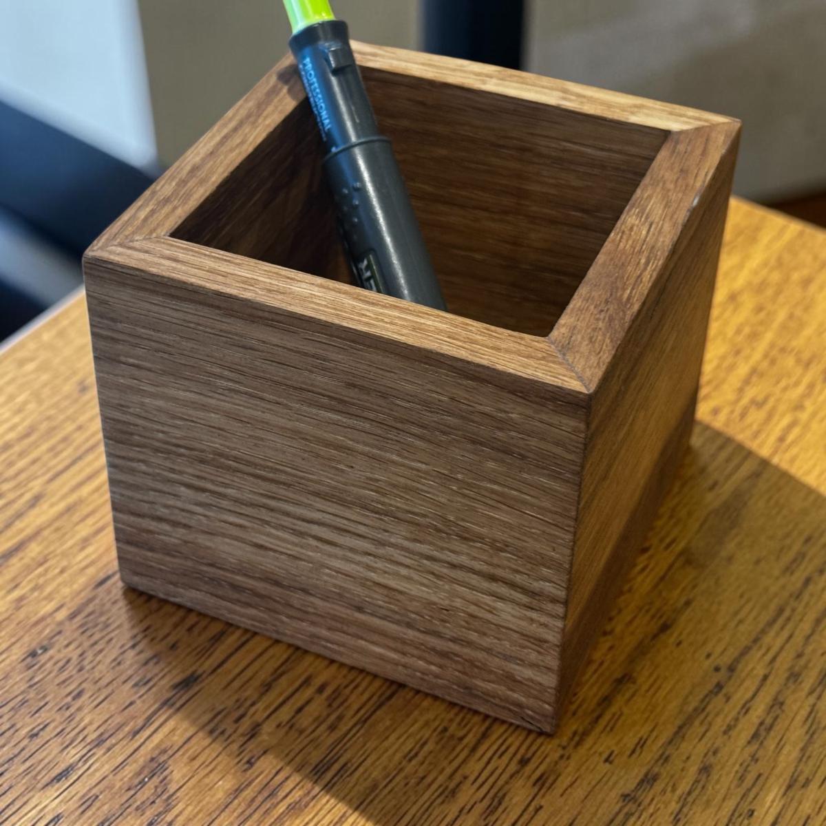 A square oak desk organiser on a wooden desk.