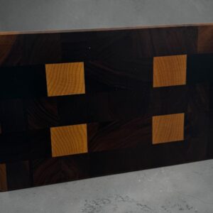 End grain chopping board made of walnut and maple stood up on a worktop.