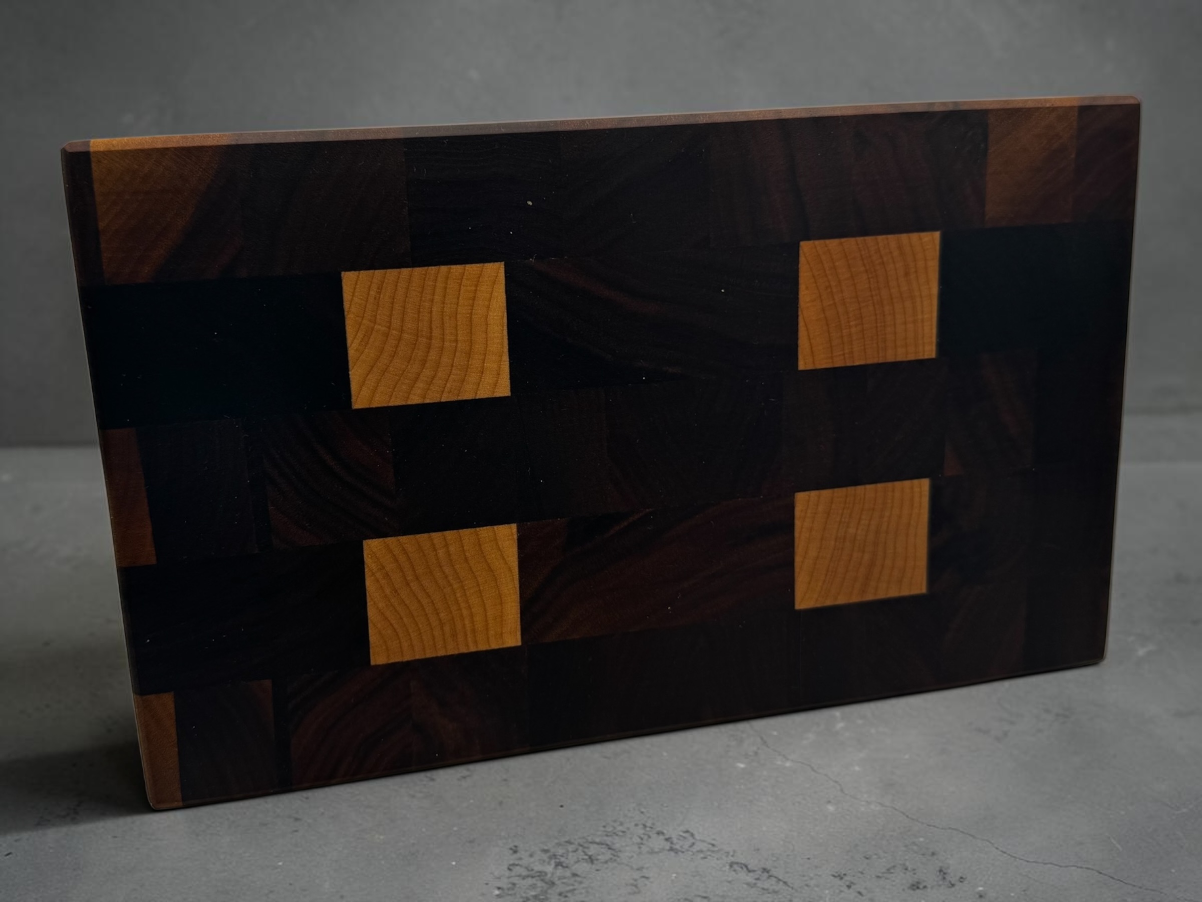 End grain chopping board made of walnut and maple stood up on a worktop.