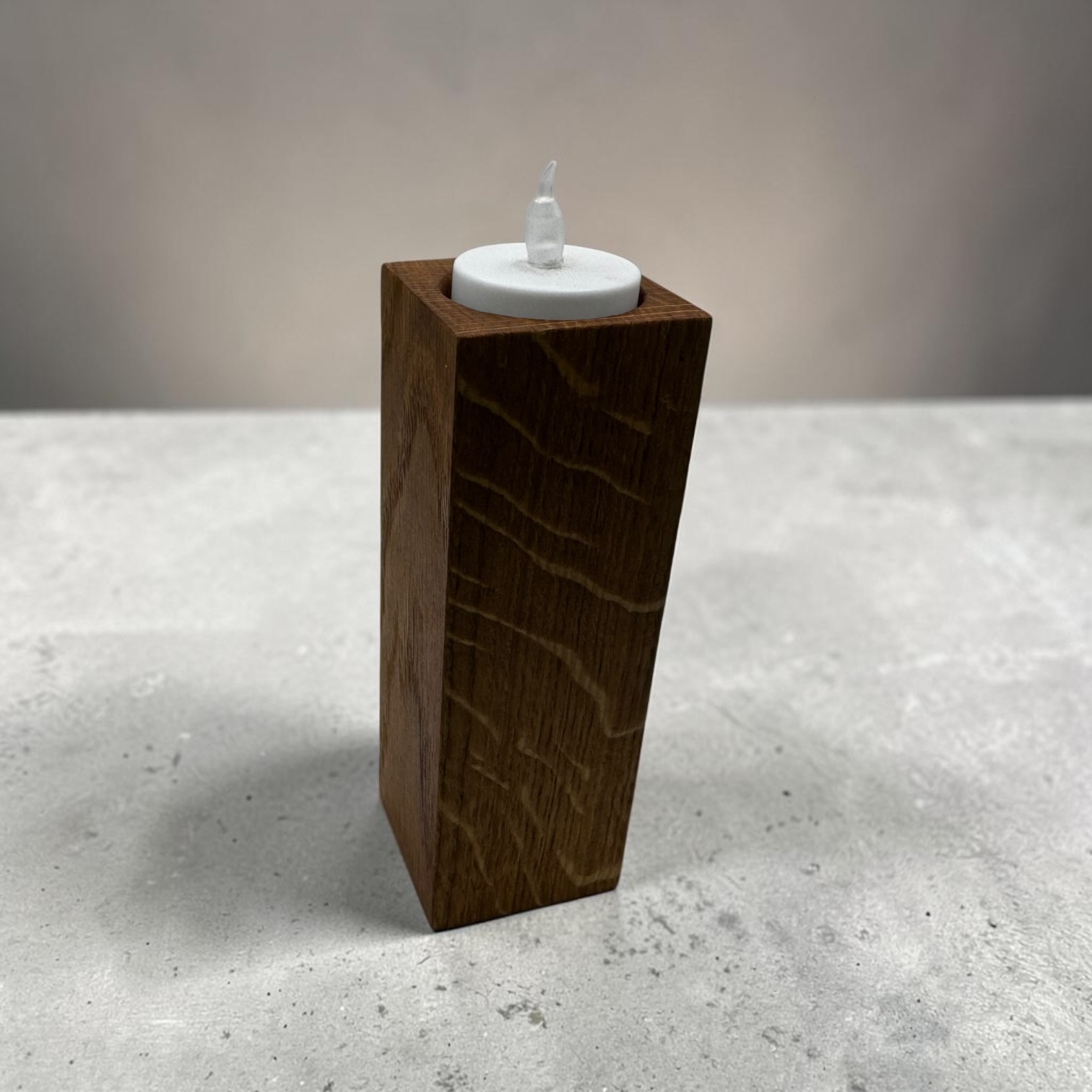 A large tea light holder that is tall and square with an electric tea light in the top.