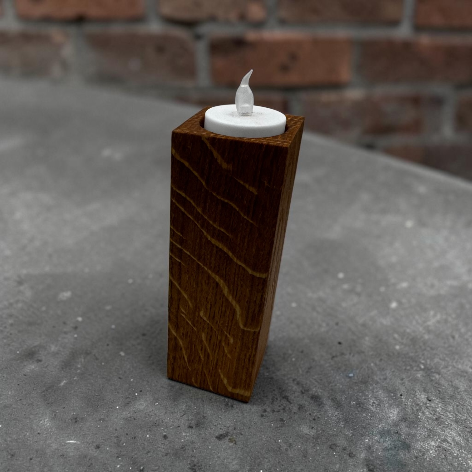A large tea light holder that is tall and square with an electric tea light in the top.