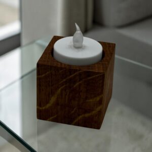 A small tea light holder that is tall and square with an electric tea light in the top on a glass table.