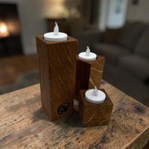 A trio of tea light holders, small, medium and large at a rustic wooden table.