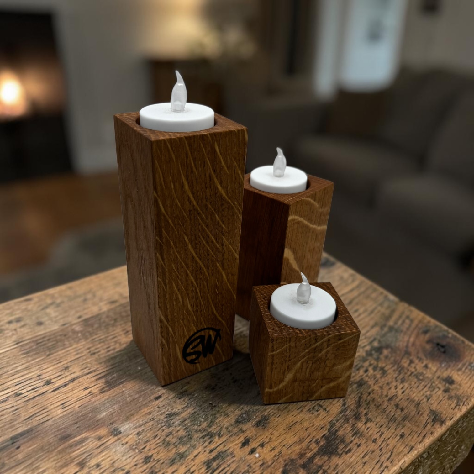 A trio of tea light holders, small, medium and large at a rustic wooden table.